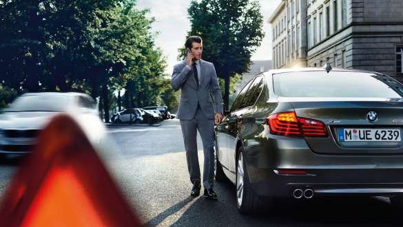 BMW palīdzība uz ceļa BMW palīdzība uz ceļa, vīrietis runā pa telefonu BMW priekšā