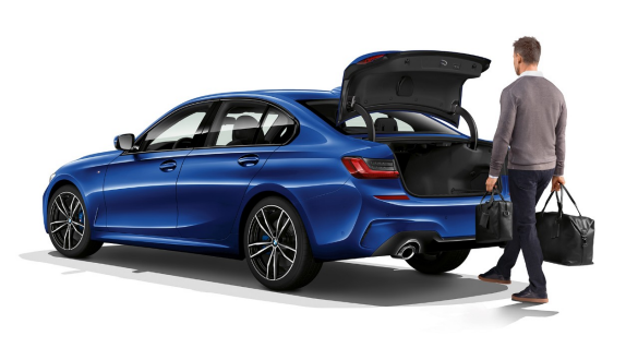 BMW 3. sērijas Sedan, automātiskas bagāžas nodalījuma durvis Trīs ceturtdaļu skats no aizmugures uz BMW 3. sērijas Sedan ar vadītāju, kurš ar savu kāju automātiski atver bagāžas nodalījumu.