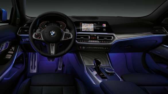 BMW 3. sērijas Sedan, fona apgaismojums Skats no priekšpuses uz BMW 3. sērijas Sedan vadītāja kokpitu, kurā vietu kājām izgaismo zils fona apgaismojums.