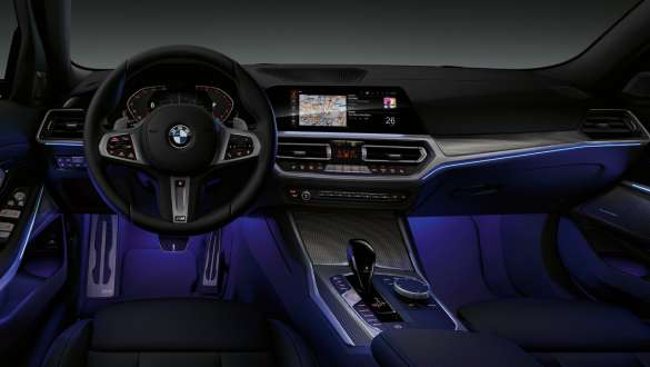 BMW 3. sērijas Sedan (G20), fona apgaismojums. Skats no priekšpuses uz BMW 3. sērijas Sedan (G20) vadītāja kokpitu, kurā vietu kājām izgaismo zils fona apgaismojums.