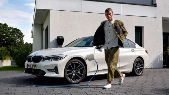 Hibrīdauto, BMW 3. sērijas Sedan, 2021, G20, trīs ceturtdaļu priekšpuses skats, uzlādes laikā Hibrīdauto, BMW 3. sērijas Sedan, 2021, G20, trīs ceturtdaļu priekšpuses skats, uzlādes laikā ar modeli