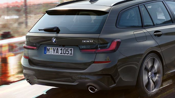 BMW 3. sērijas Touring, trīs ceturtdaļu aizmugures skats. BMW 3. sērijas Touring, trīs ceturtdaļu skats no aizmugures uz braucošu automobili uz tilta uz lauku apvidus fona