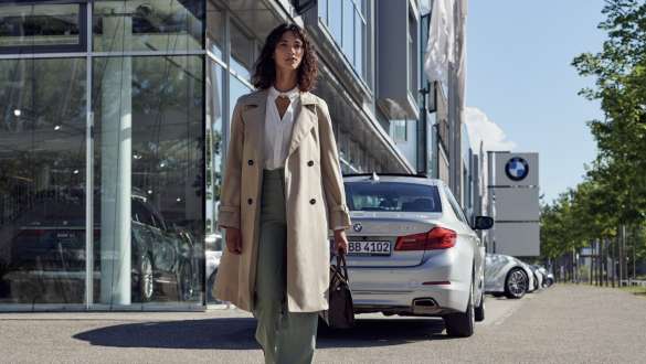 Sieviete uz BMW automobiļu pārstāvniecības fona BMW Service Inclusive, sieviete uz BMW automobiļu pārstāvniecības fona