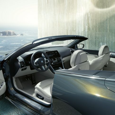 BMW M850i xDrive Cabrio, salons. BMW M850i xDrive Cabrio metāliskā Dravit Grey krāsā ar nolaistu mīkstā seguma jumtu, salons ar M ādas stūri un BMW Individual Merino ādas apdari Ivory White krāsā.