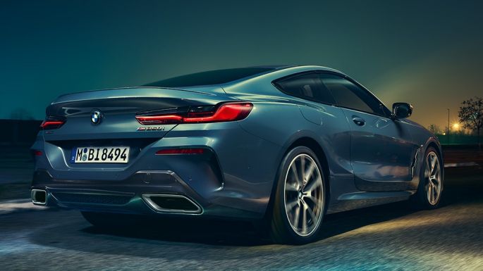 BMW M850i xDrive Coupé, aizmugures skats. BMW M850i xDrive Coupé Coupé metāliskā Barcelona Blue krāsā, aizmugures skats, braucošs automobilis naktī.