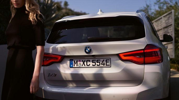 Aizmugure ar BMW i īpašo difuzoru, BMW iX3, G08, 2020, aizmugure ar sievieti Aizmugure ar BMW i īpašo difuzoru, BMW iX3, G08, 2020, metāliska Mineral White krāsa, aizmugure ar sievieti