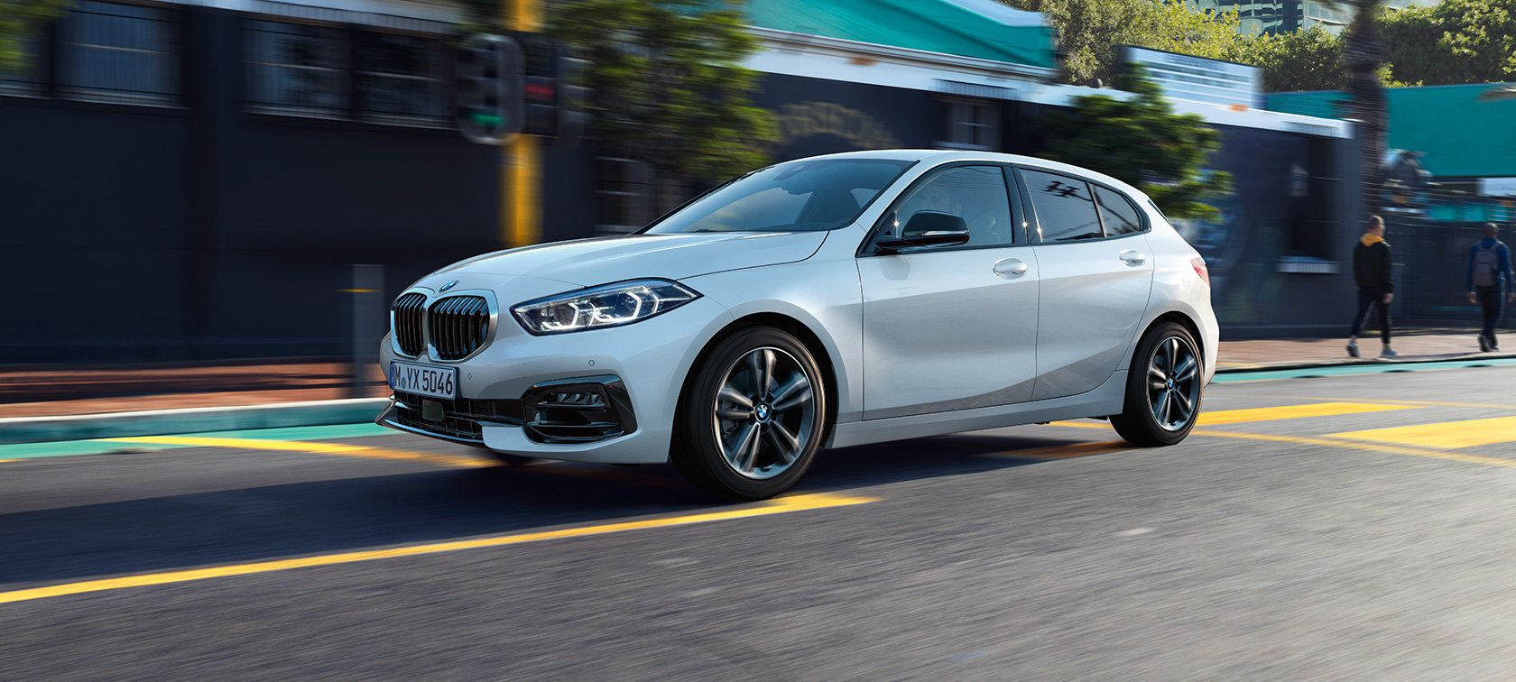 BMW 1. sērijas Sport Line modelis, trīs ceturtdaļu sānu skats. BMW 1. sērijas Sport Line modelis metāliskā Mineral White krāsā, trīs ceturtdaļu skats uz braucošu automobili.