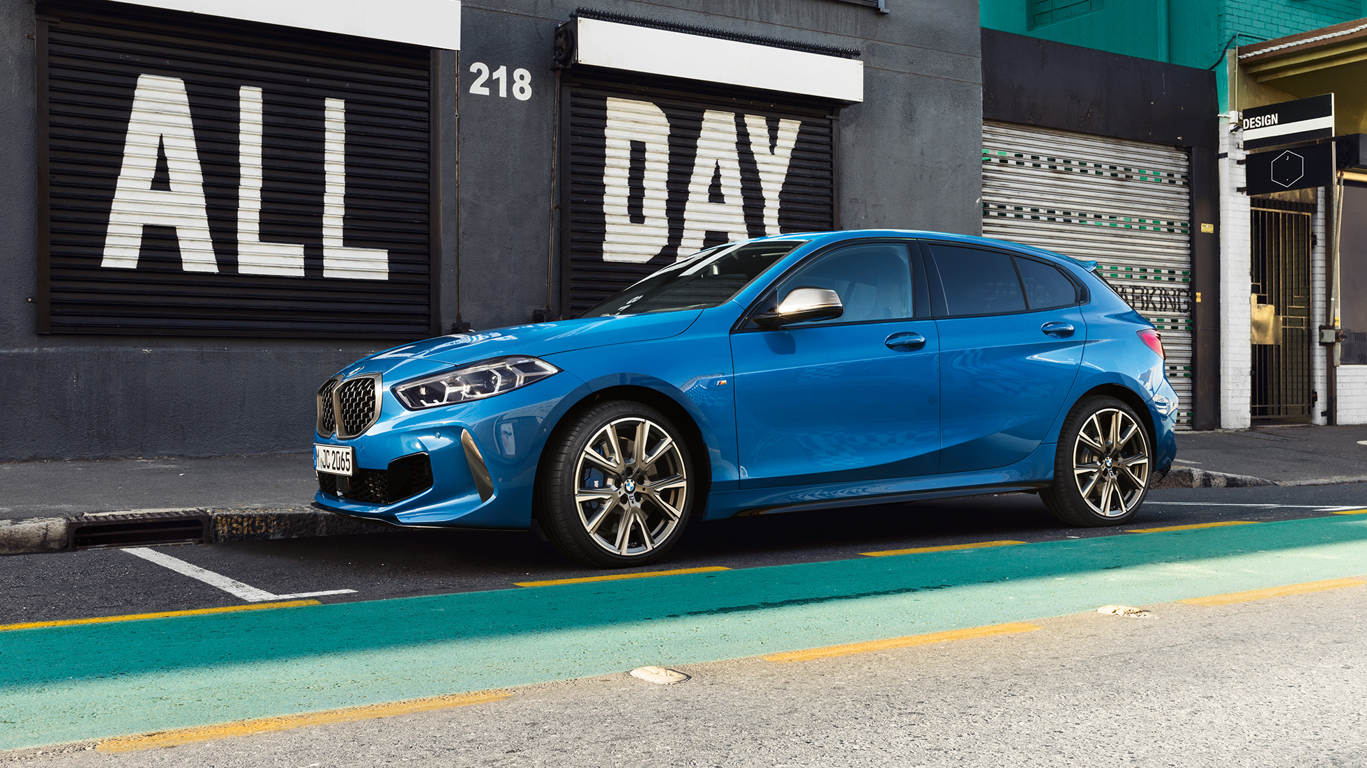 1. sērijas BMW novietošana. 1. sērijas BMW metāliskā Misano Blue krāsā, sānskats stāvvietā.