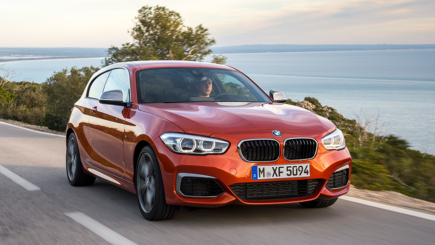 BMW M135i (F21), trīs ceturtdaļu priekšpuses skats, braucienā, uz ezera un kalnu fona BMW M135i (F21), trīs ceturtdaļu priekšpuses skats, braucienā, uz ezera un kalnu fona