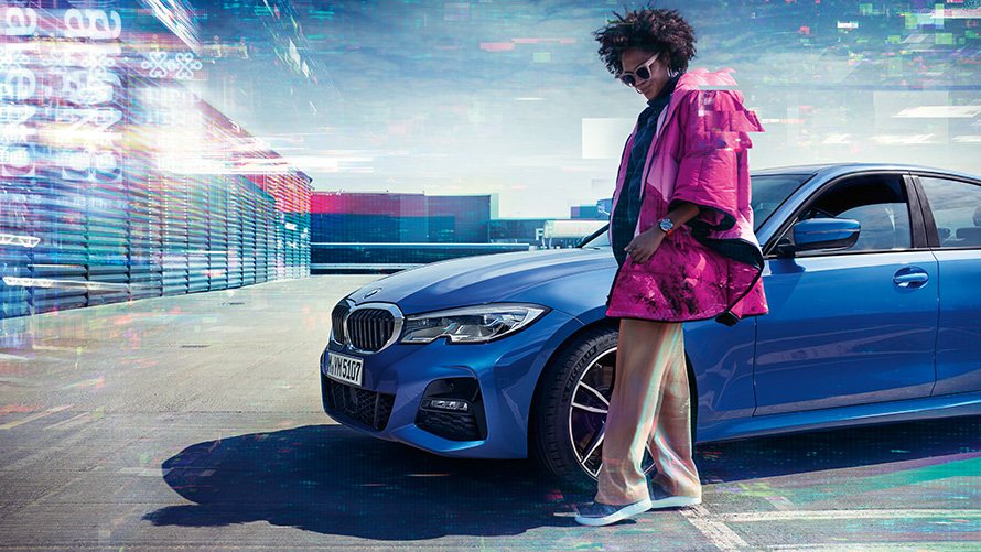 BMW 3. sērijas Sedan (G20), metāliska Portimao Blue krāsa, 7/8 priekšpuses skats BMW 3. sērijas Sedan (G20), metāliska Portimao Blue krāsa, 7/8 priekšpuses skats uz atklātu stāvvietu ar cilvēku priekšplānā
