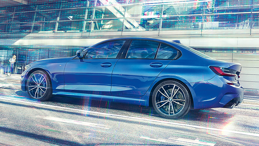 BMW 3. sērijas Sedan (G20) dienā uz stiklotas ēkas fona. Skats uz stāvošu BMW 3. sērijas Sedan (G20) Portimao Blue krāsā dienā uz stiklotas ēkas fona.