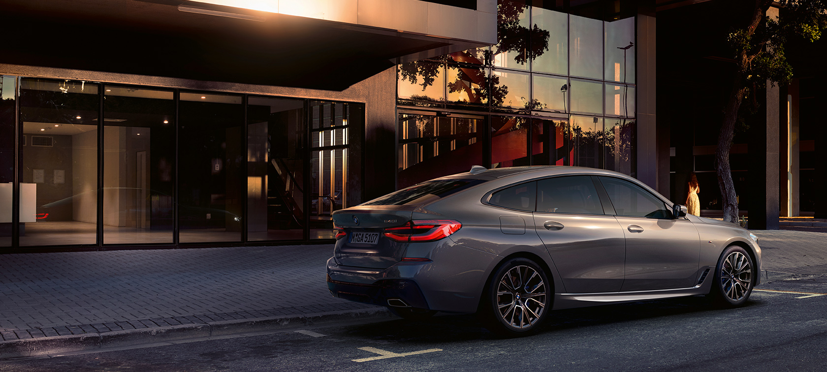 BMW 6. sērijas Gran Turismo G32, 2020 BMW 6. sērijas Gran Turismo 640i xDrive, G32, 2020, Bernina Grey krāsā, aizmugures skats no sāniem, ēkas priekšā novietots automobilis
