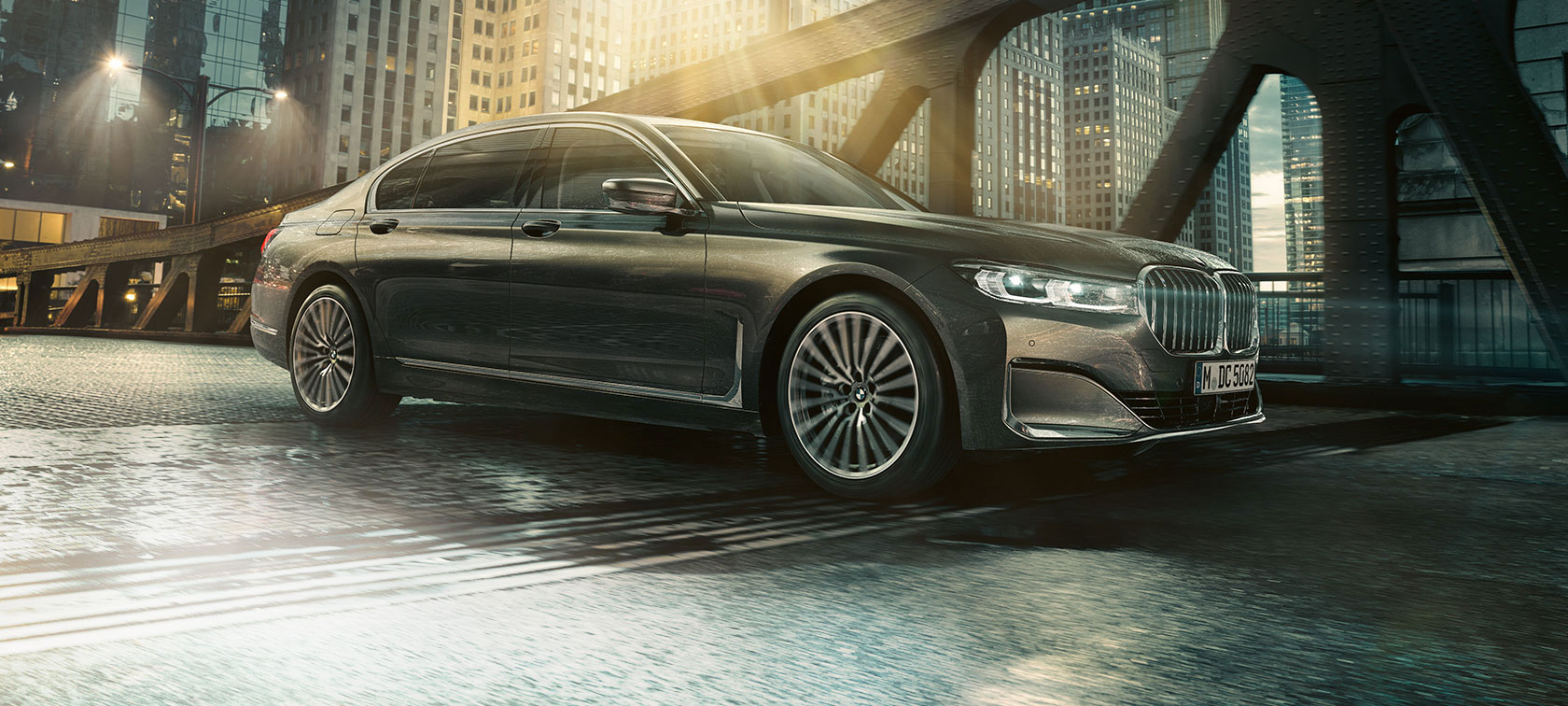 BMW 7. sērijas Sedan skats no sāna BMW 7. sērijas Sedan sānskatā ar atvērtām durvīm uz izgaismotas viesnīcas fona
