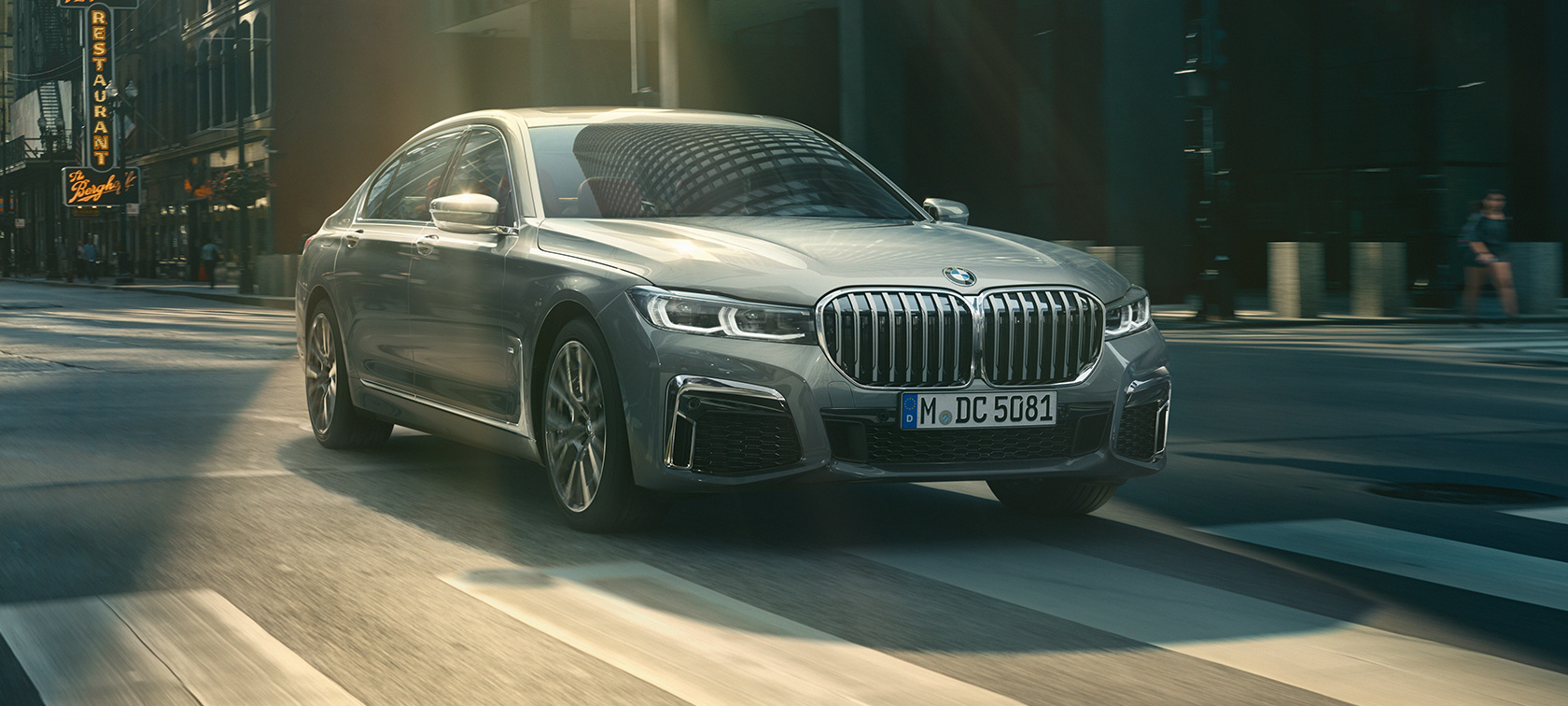 BMW 7. sērijas Sedan G11, G12, 2019, Bernina Grey Amber Effect krāsā skatā no priekšpuses brauciena laikā BMW 7. sērijas Sedan G11, G12, 2019, Bernina Grey Amber Effect krāsā trīs ceturtdaļu skatā no priekšpuses brauciena laikā pilsētvidē