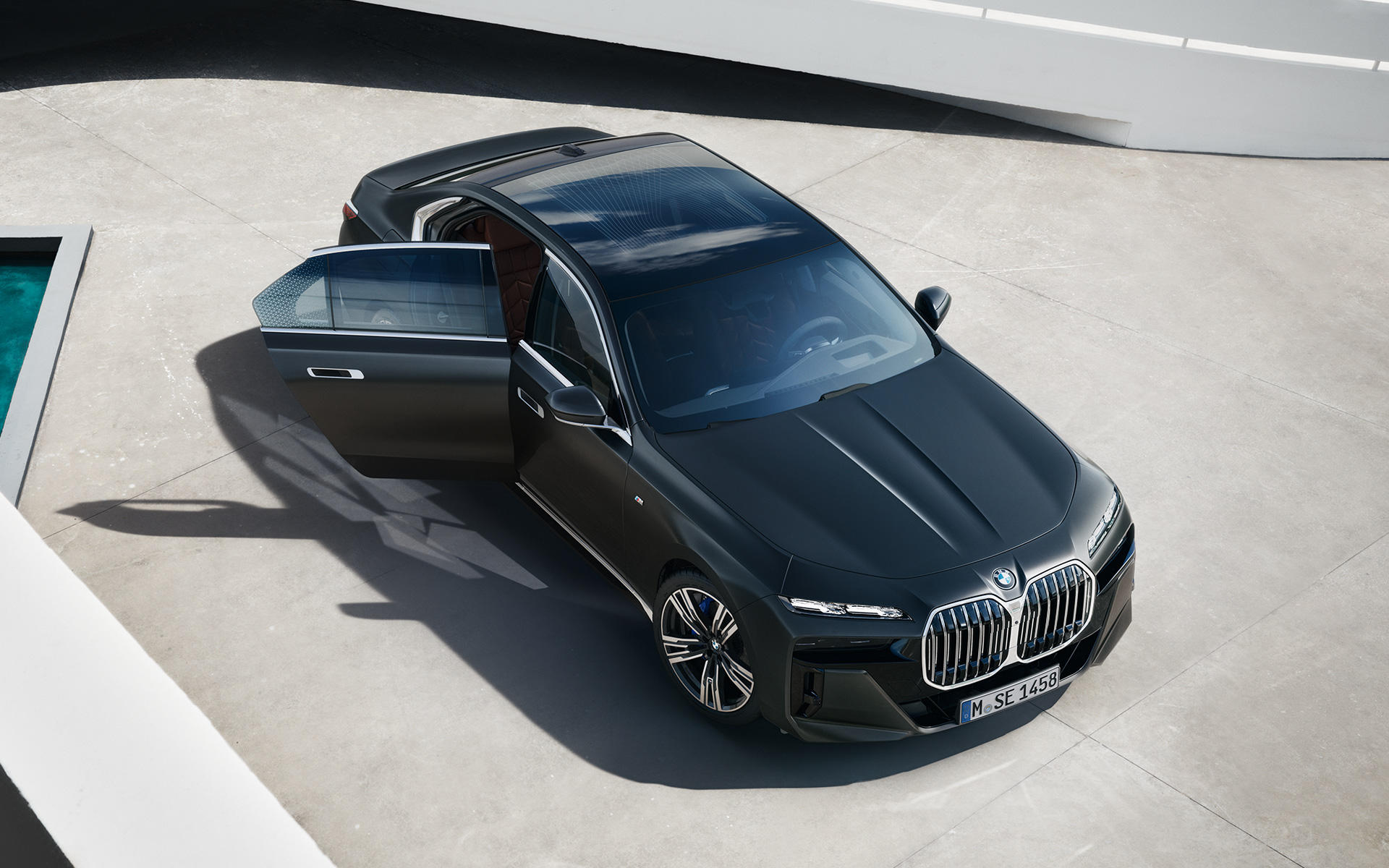 BMW 7. sērijas Sedan, G70, ICE, 740i, M sporta pakotne, metāliska Frozen Deep Grey krāsa, skats no putna lidojuma, ar atvērtām pasažiera durvīm