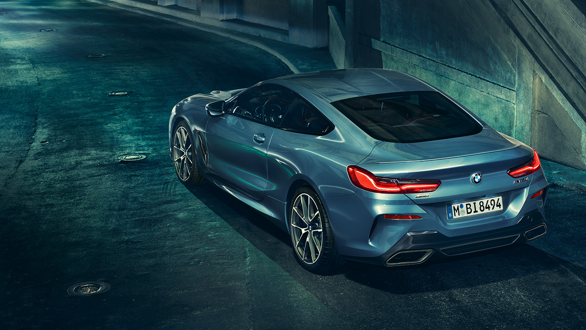 BMW 8. sērijas Coupé, trīs ceturtdaļu aizmugures skats. BMW 8. sērijas Coupé trīs ceturtdaļu skats naksnīgā pilsētā.