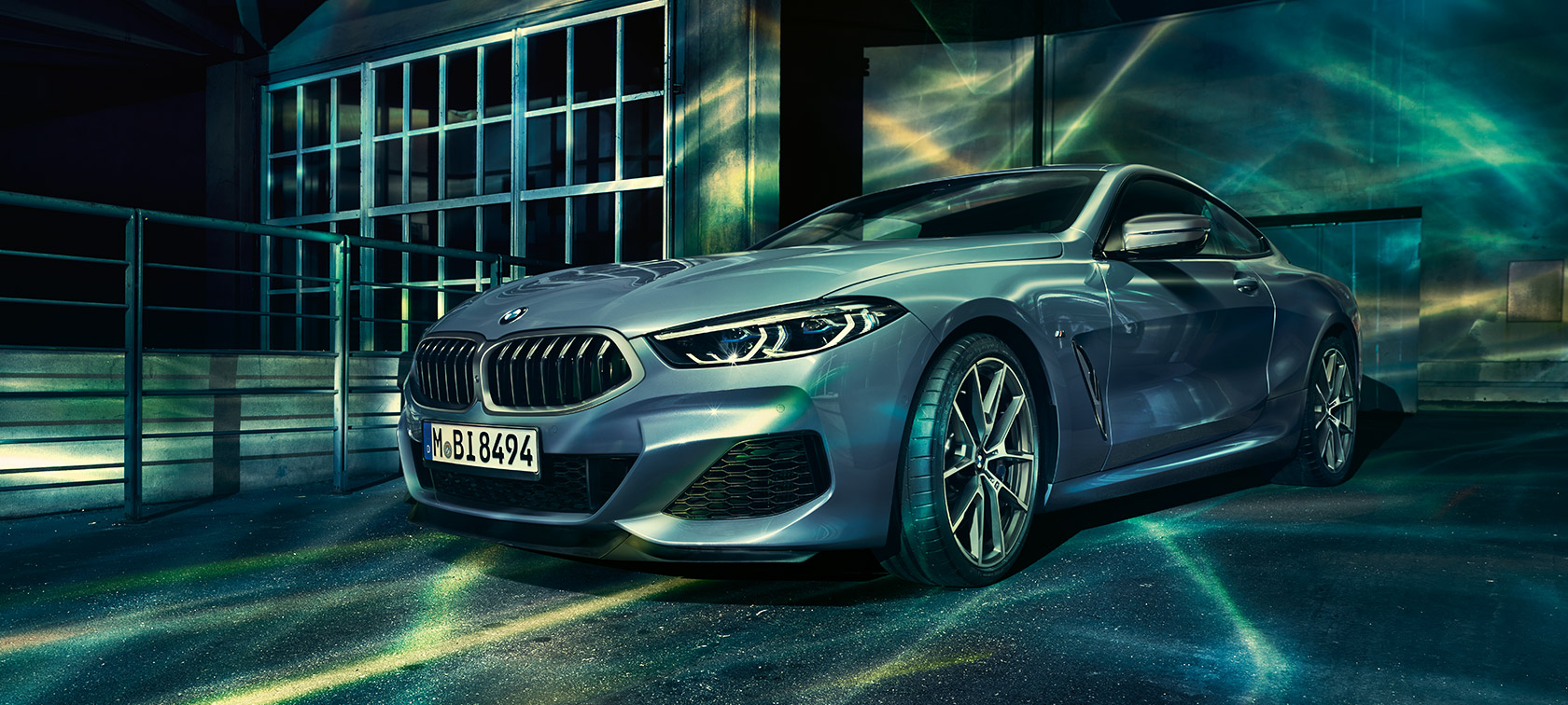 BMW 8. sērijas Coupé, trīs ceturtdaļu priekšējais skats. BMW 8. sērijas Coupé, trīs ceturtdaļu skatā no priekšpuses uz rūpnīcas ēkas fona.