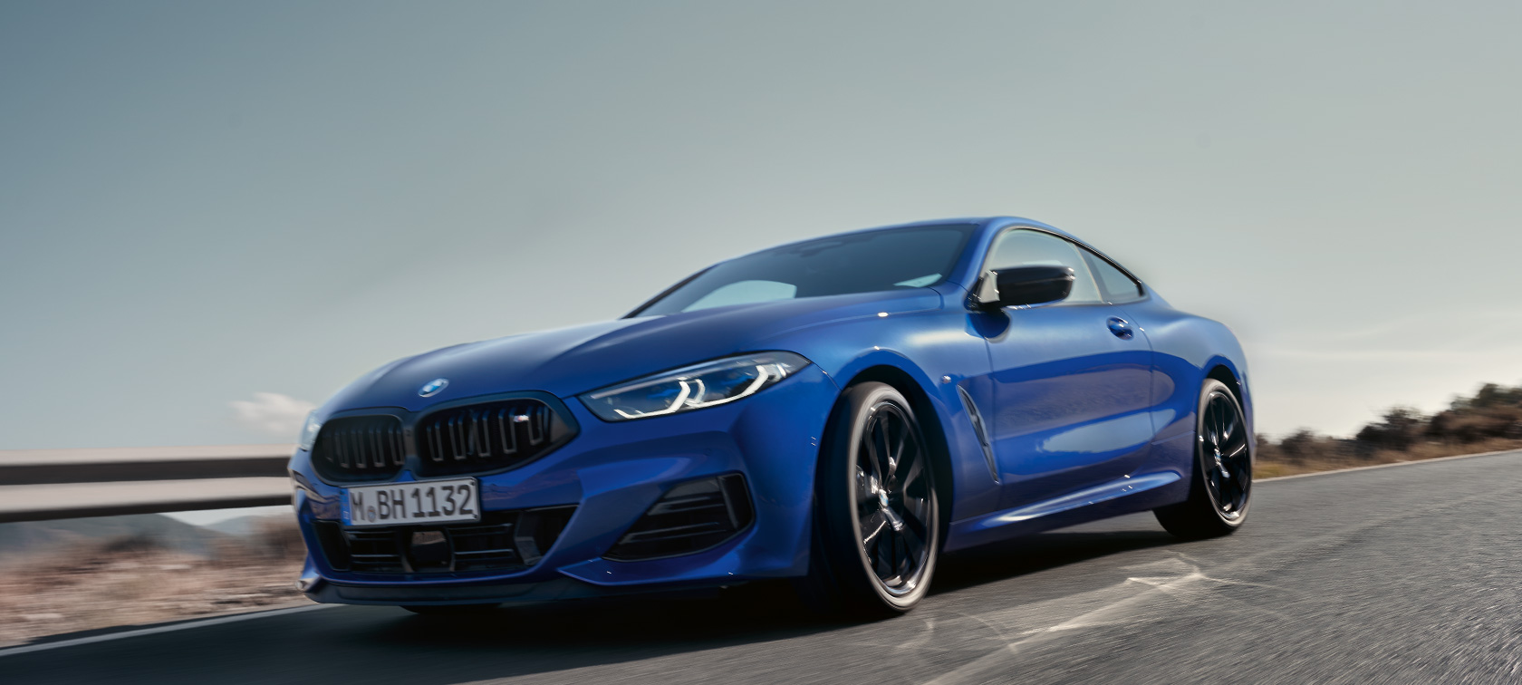 BMW 8. sērijas Coupé, G15, LCI, atjaunināts, 2022, BMW M850i xDrive, metāliska Portimao Blue krāsa, priekšpuses skats, zema leņķa uzņēmums BMW 8. sērijas G15, LCI, atjaunināts, 2022, BMW M850i xDrive, metāliska Portimao Blue krāsa, priekšpuses skats, zema leņķa uzņēmums, braucienā pa lauku ceļu uz pakalnu fona