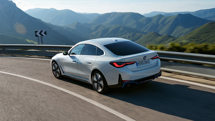 Trīs ceturtdaļu aizmugures skats uz braucošu BMW i4 eDrive40, G26, 2021 BMW i4 eDrive40, G26, 2021, Mineral White krāsa, trīs ceturtdaļu aizmugures skats, braucienā