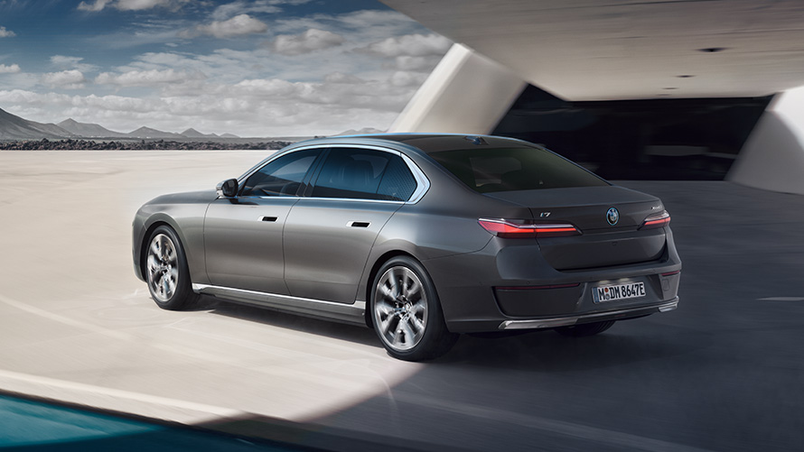 BMW i7 Sedan, G70, BMW Individual metāliska Oxid Grey krāsa, trīs ceturtdaļu aizmugures skats, stāvošs automobilis uz ēkas fona BMW i7 Sedan, pakotne, trīs ceturtdaļu aizmugures skats