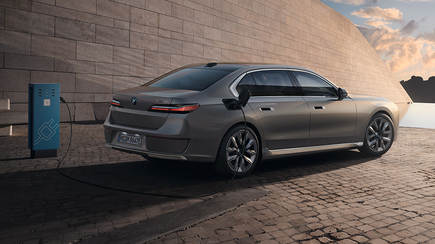 BMW i7 Sedan, G70, trīs ceturtdaļu sānskats, no aizmugures BMW i7 Sedan, G70, BMW Individual metāliska Oxid Grey krāsa, trīs ceturtdaļu sānskats, no aizmugures, uzlādes stacijā