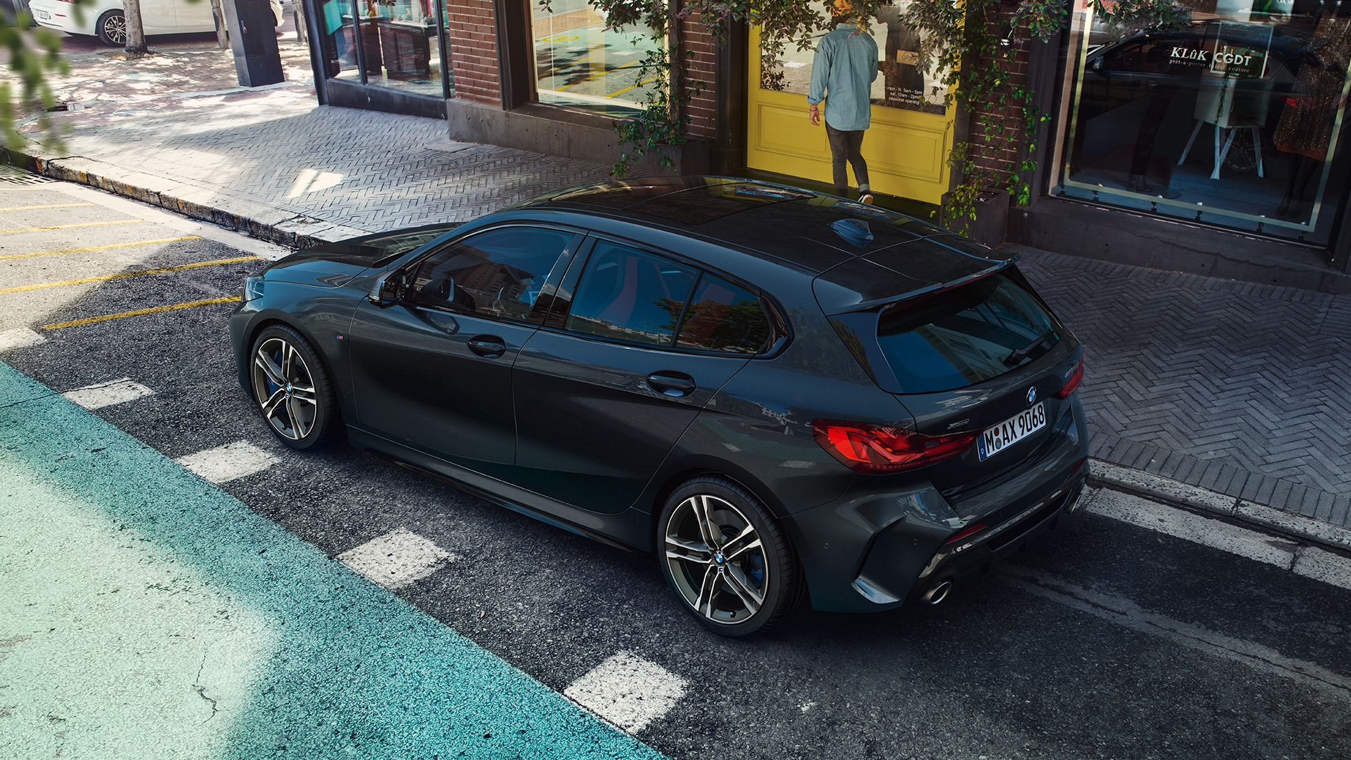 BMW M135i xDrive, novietots stāvvietā. BMW M135i xDrive metāliskā Black Sapphire krāsā, novietots stāvvietā, sānskatā no putna lidojuma.