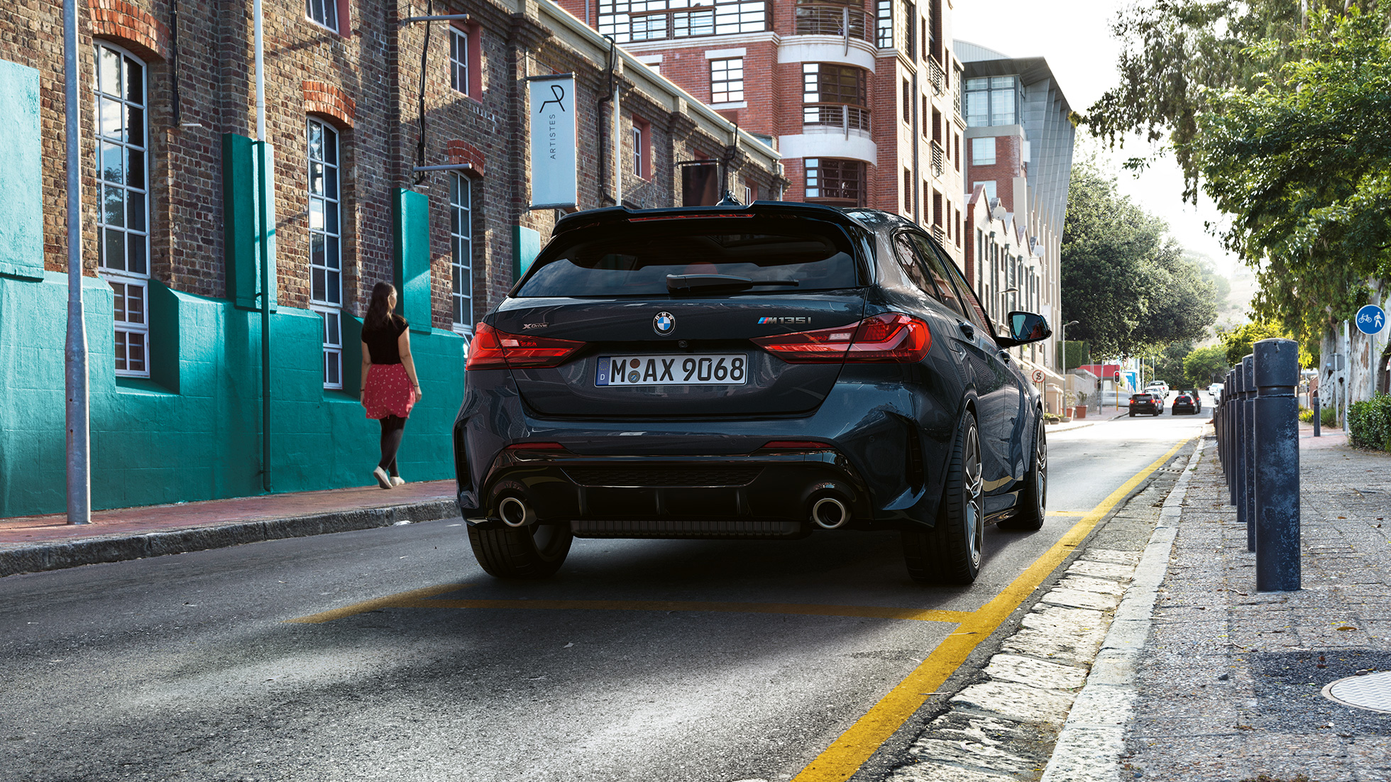 BMW M135i xDrive, aizmugures skats. BMW M135i xDrive metāliskā Black Sapphire krāsā, novietots stāvvietā skatā no aizmugures.
