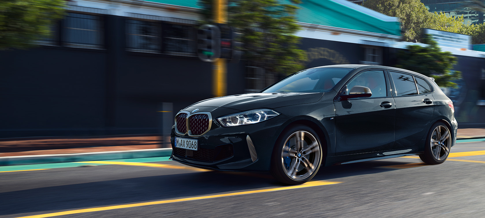Pilnīgi jaunais BMW M135i xDrive Pilnīgi jaunais BMW M135i xDrive metāliskā Black Sapphire krāsā, trīs ceturtdaļu skats no sāna uz braucošu automobili.