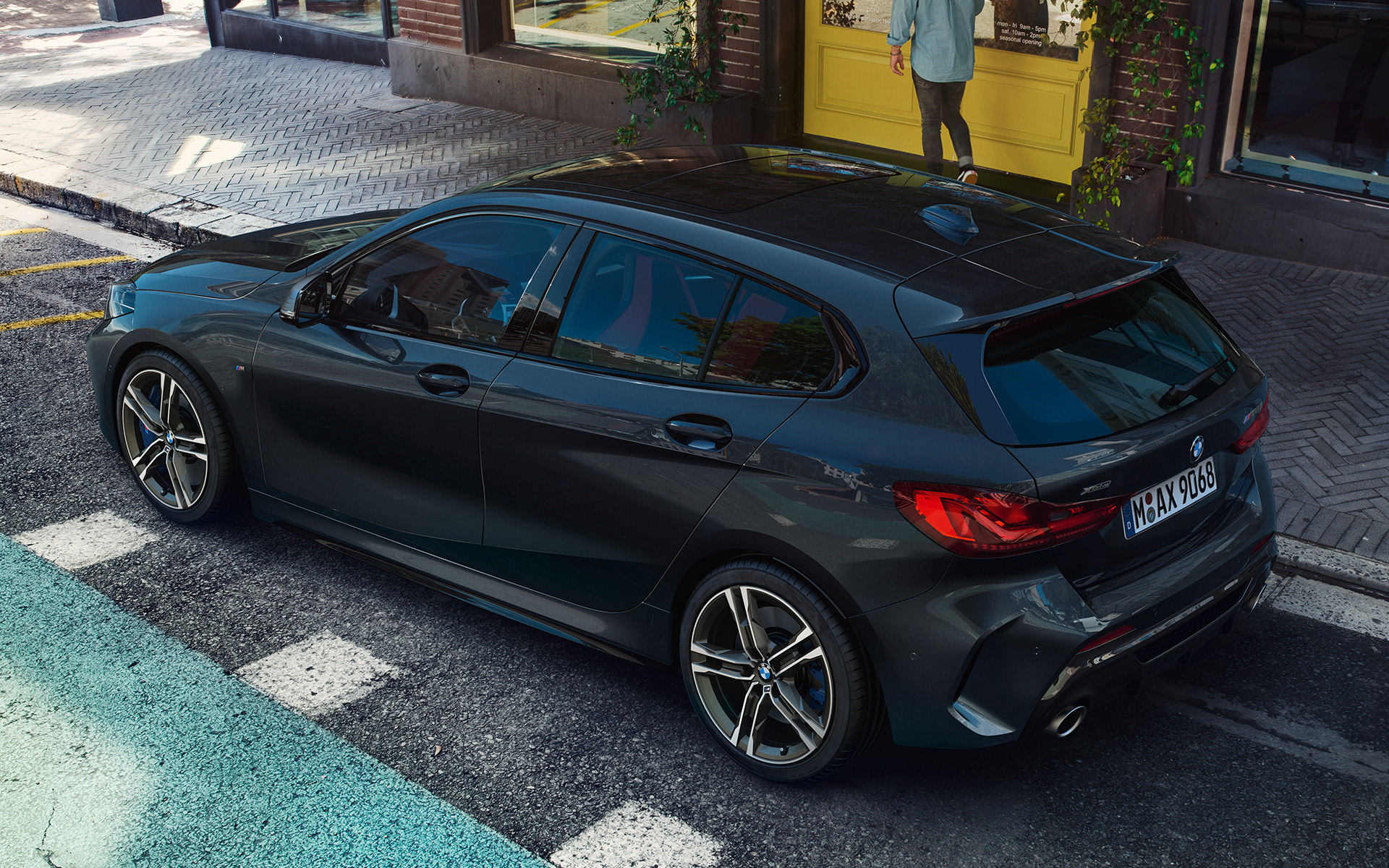 BMW M135i xDrive (F40) metāliskā Black Sapphire krāsā, novietots stāvvietā, sānskatā no putna lidojuma