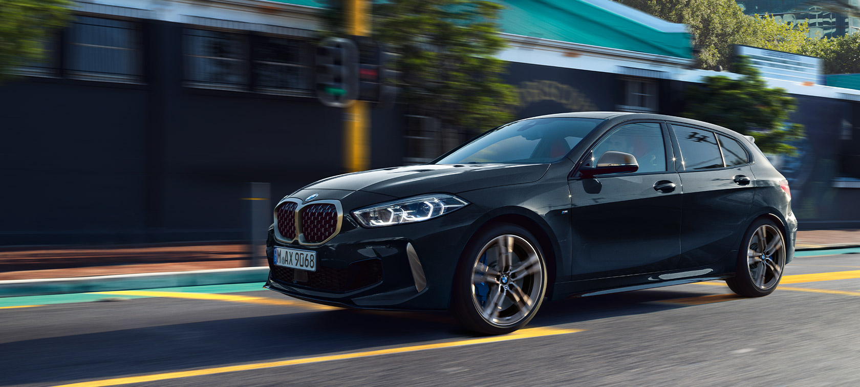 BMW 1. sērijas M135i xDrive (F40), metāliskā Black Sapphire krāsā, braucošs automobilis pilsētas vidē