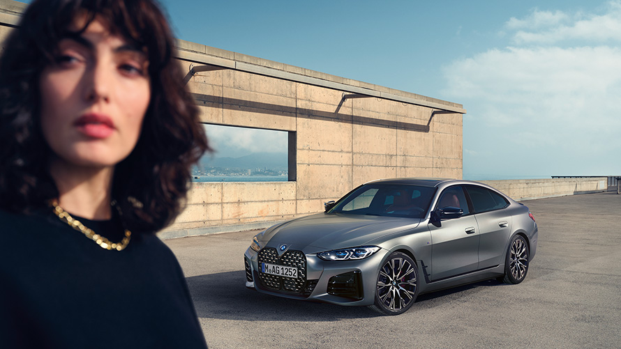 BMW M440i xDrive Gran Coupé, G26, 2021, trīs ceturtdaļu priekšpuses skats ar modeli BMW M440i xDrive Gran Coupé, G26, 2021, metāliska Frozen Pure Grey krāsa, trīs ceturtdaļu priekšpuses skats, ar modeli