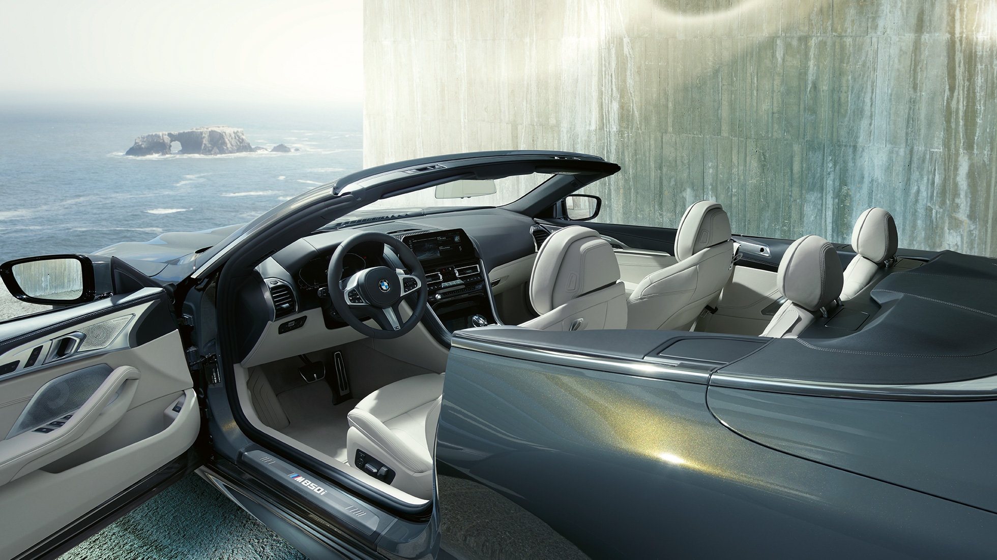 BMW M850i xDrive Cabrio, salons. BMW M850i xDrive Cabrio metāliskā Dravit Grey krāsā ar nolaistu mīkstā seguma jumtu, salons ar M ādas stūri un BMW Individual Merino ādas apdari Ivory White krāsā.