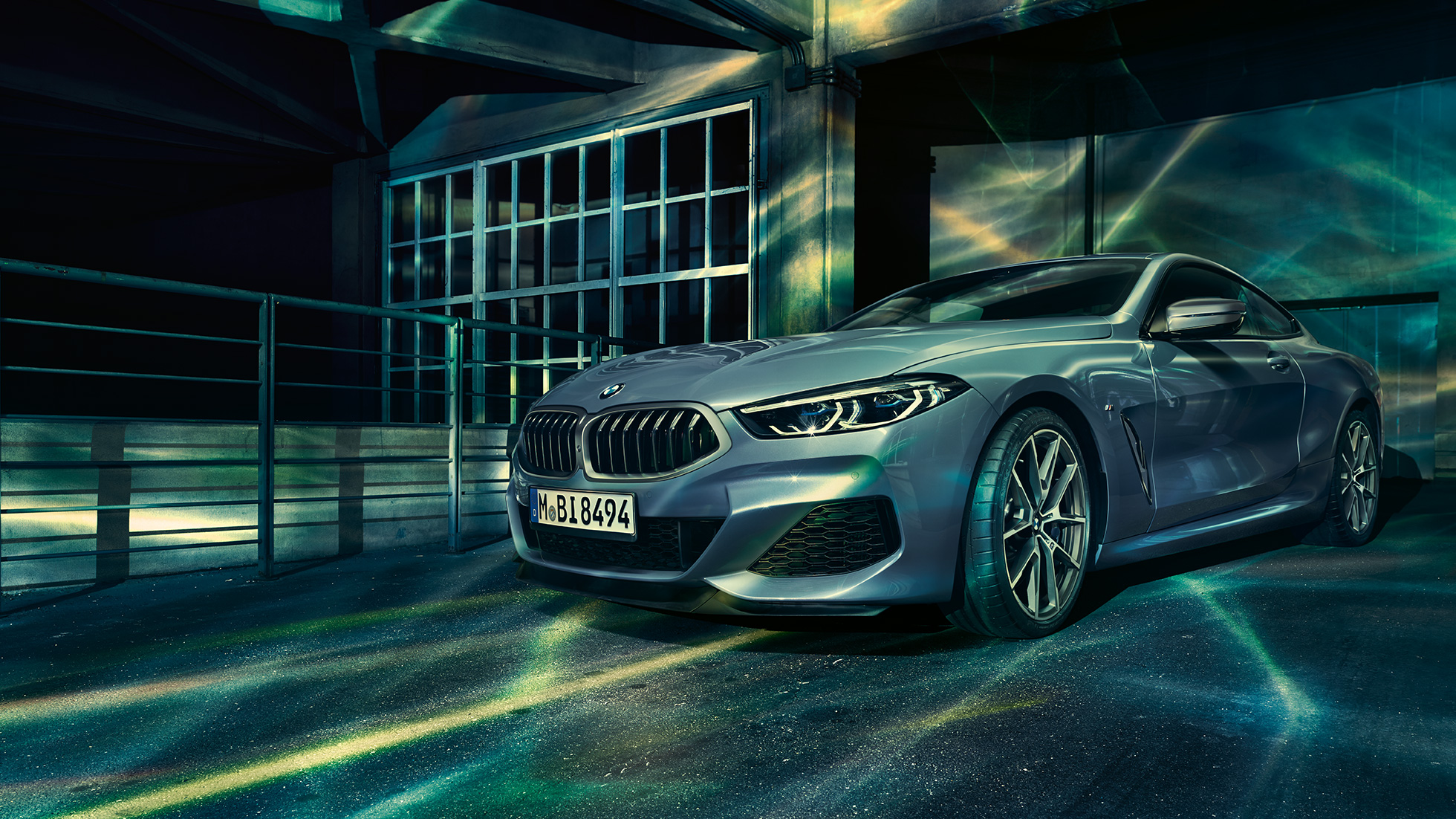 BMW M850i xDrive Coupé, trīs ceturtdaļu skats no priekšpuses. BMW M850i xDrive metāliskā Barcelona Blue krāsā, trīs ceturtdaļu skats uz novietotu automobili no priekšpuses uz ēkas fona.