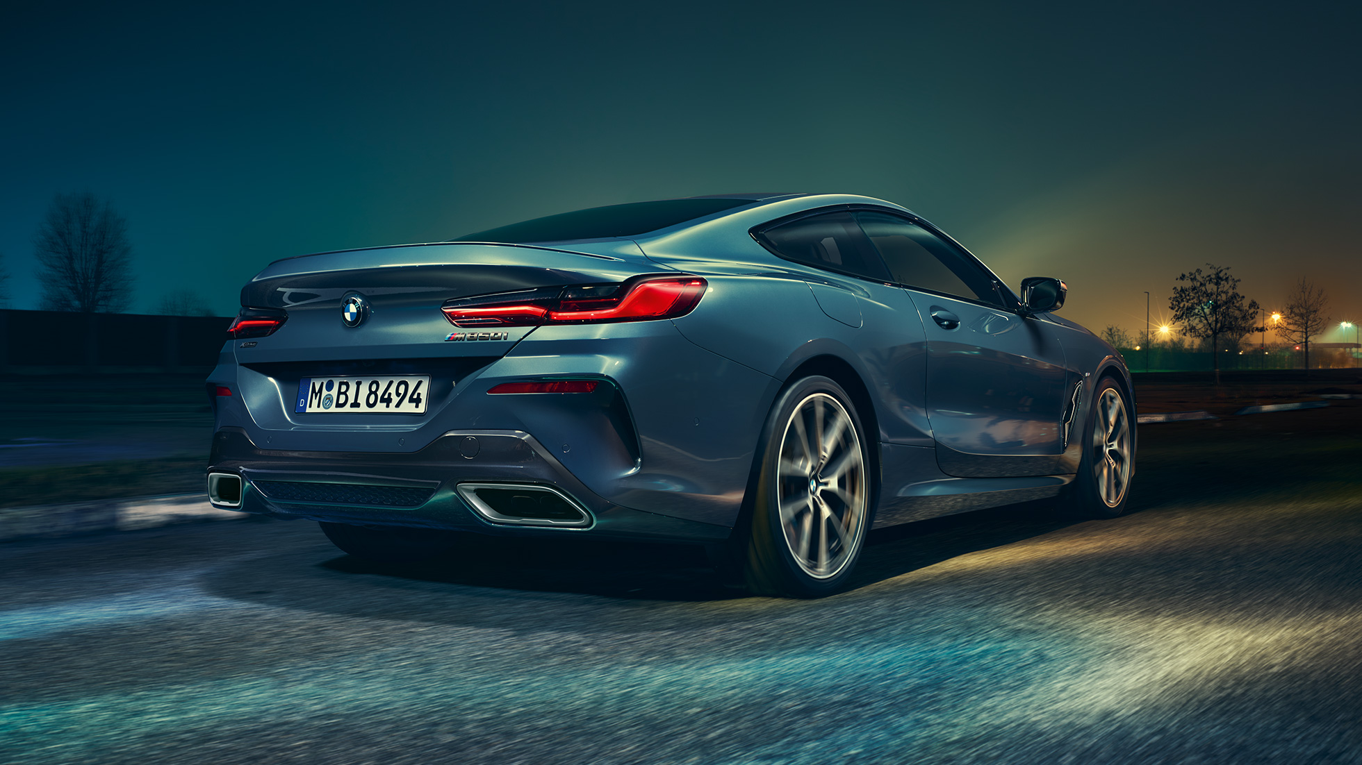 BMW M850i xDrive Coupé, aizmugures skats. BMW M850i xDrive Coupé Coupé metāliskā Barcelona Blue krāsā, aizmugures skats, braucošs automobilis naktī.