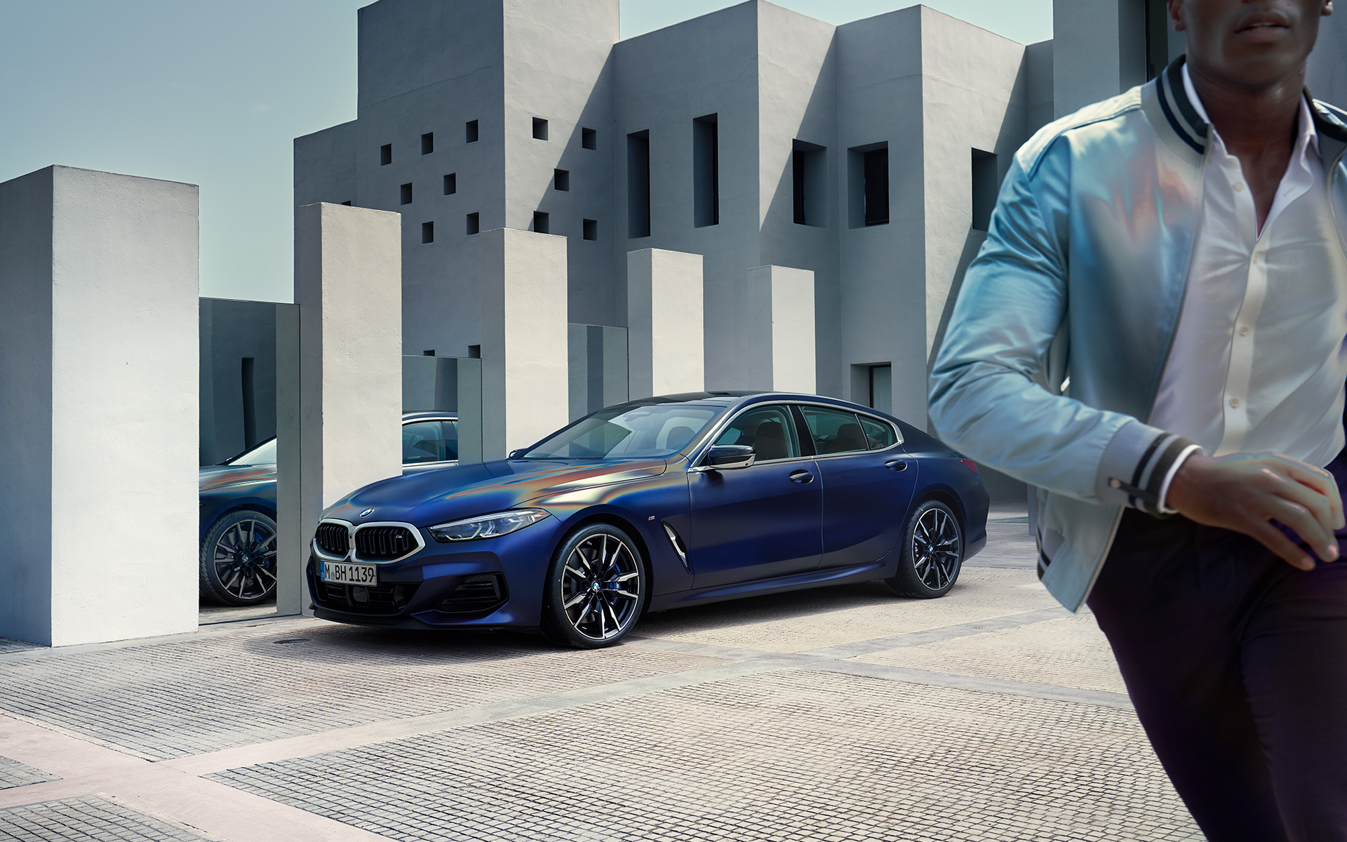 Jaunā BMW M850i xDrive Gran Coupé G16, LCI, atjaunināts, 2022, BMW Individual metāliska Frozen Tanzanite Blue krāsa, trīs ceturtdaļu priekšpuses skats, stāvošs automobilis, ar modeli vīrieti priekšplānā