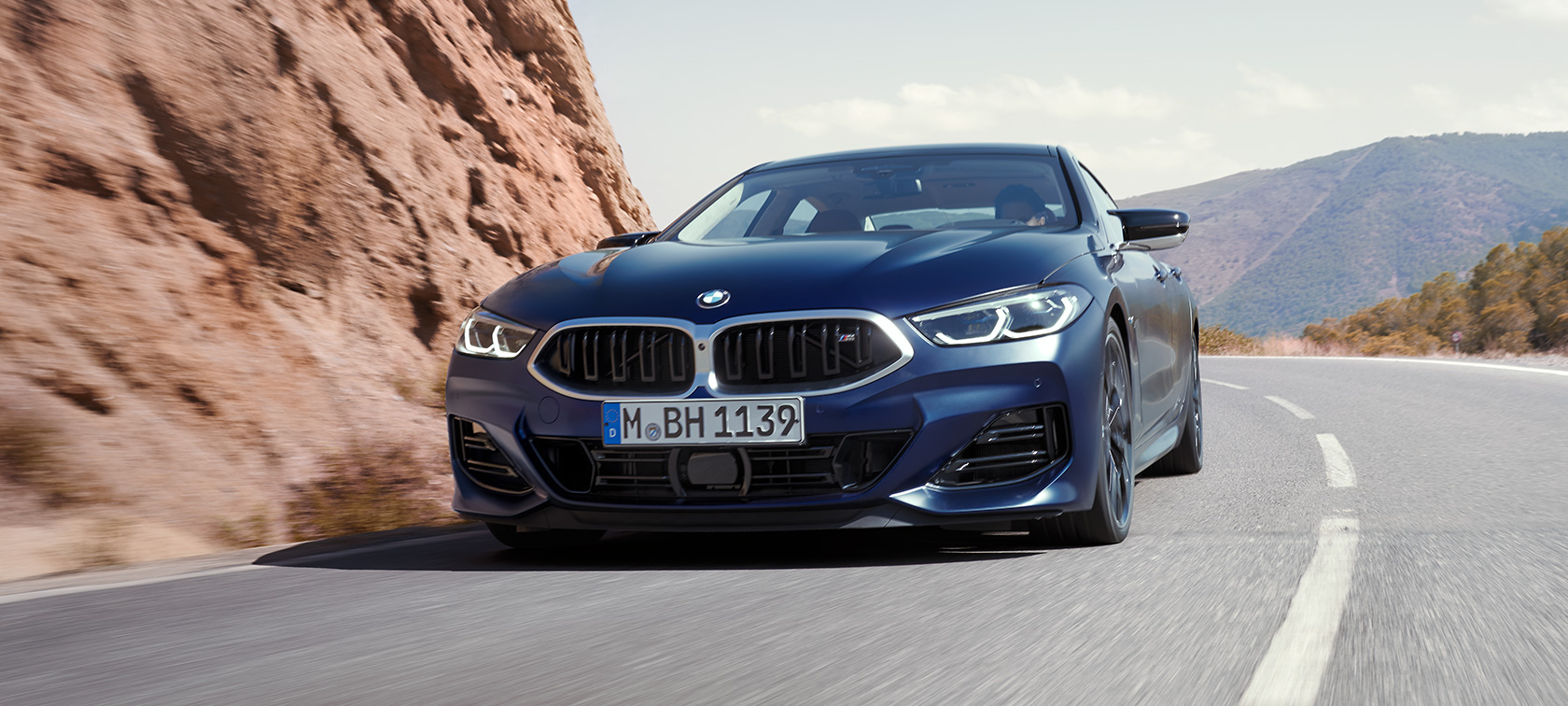 Jaunā BMW M850i xDrive Gran Coupé G16, LCI, atjaunināts, 2022, BMW Individual metāliska Frozen Tanzanite Blue krāsa, trīs ceturtdaļu priekšpuses skats, izbraucot līkumu