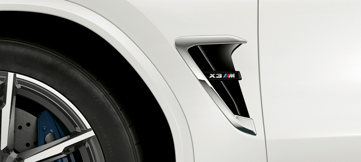 BMW X3 M sānu gaisa savācējs. BMW X3 M Alpine White krāsā, virsbūve, M gaisa savācēji ar hromētiem akcentiem un modeļa uzrakstu.