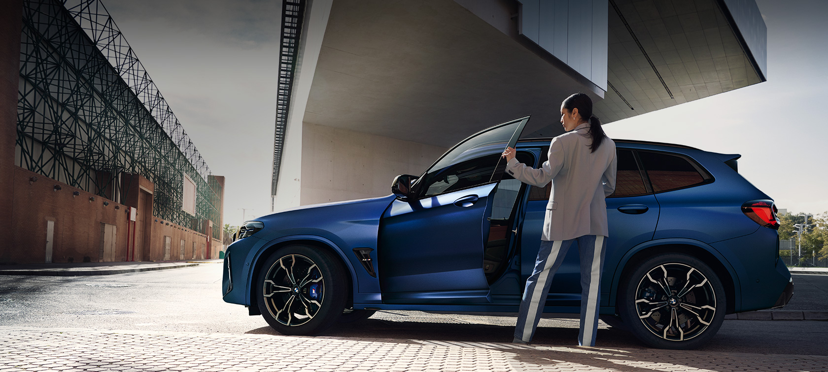 BMW X3 Competition, F97, LCI, atjaunināts, 2021, sānskats, stāvošs automobilis BMW X3 M Competition, F97, LCI, atjaunināts, 2021 BMW Individual metāliska Frozen Portimao Blue krāsa, sānskats, stāvošs automobilis, ar atvērtām durvīm un sievieti modeli
