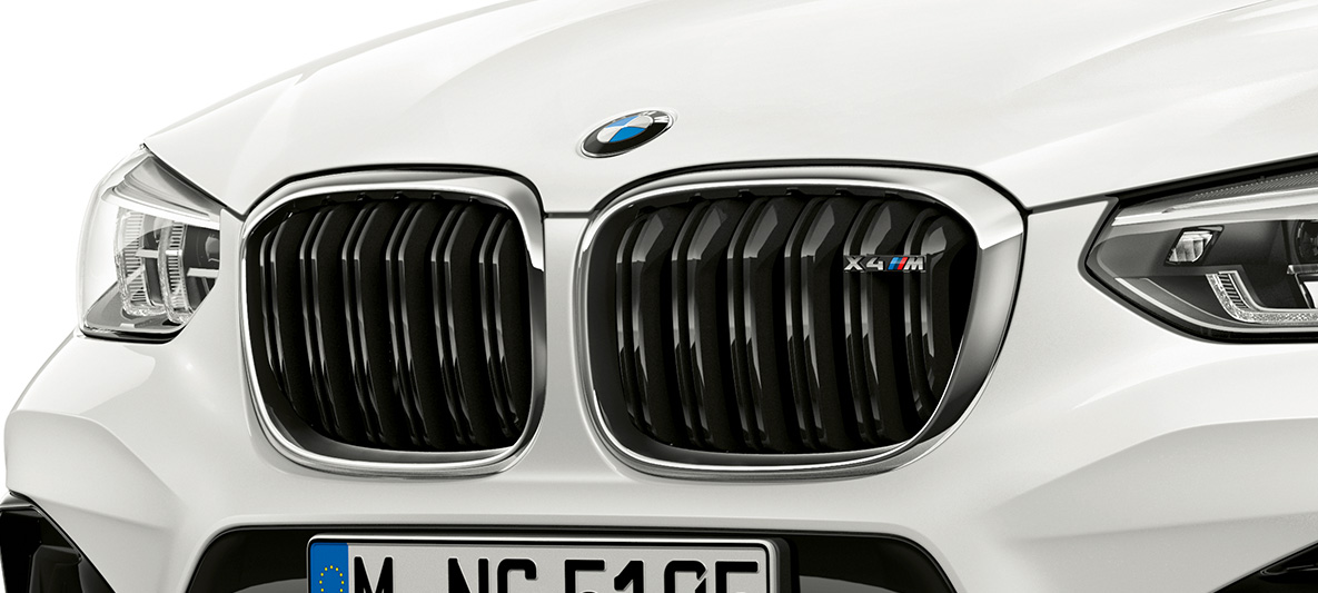 BMW X4 M, M elipsveida režģis. BMW X4 M Alpine White krāsā, virsbūve, priekšdaļa, M elipsveida režģis ar hromētiem akcentiem un modeļa uzrakstu.