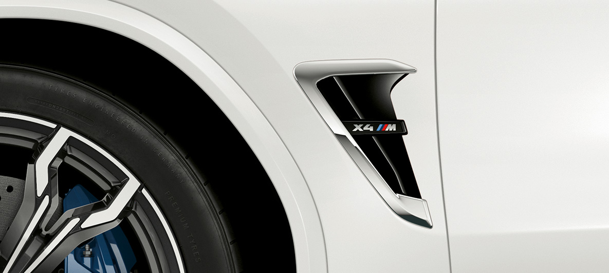 BMW X4 M sānu gaisa savācējs. BMW X4 M Alpine White krāsā, virsbūve, M gaisa savācējs ar hromētiem akcentiem un modeļa uzrakstu.