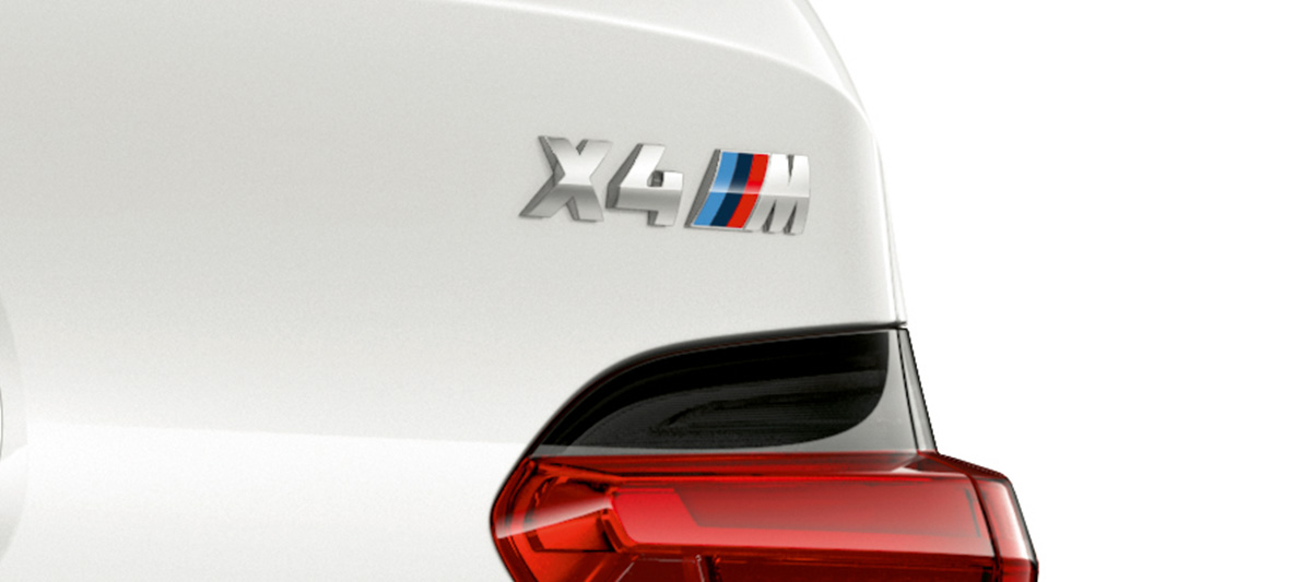 BMW X4 M, modeļa uzraksts. BMW X4 M Alpine White krāsā, virsbūve, aizmugures ar modeļa uzrakstu tuvplāns.