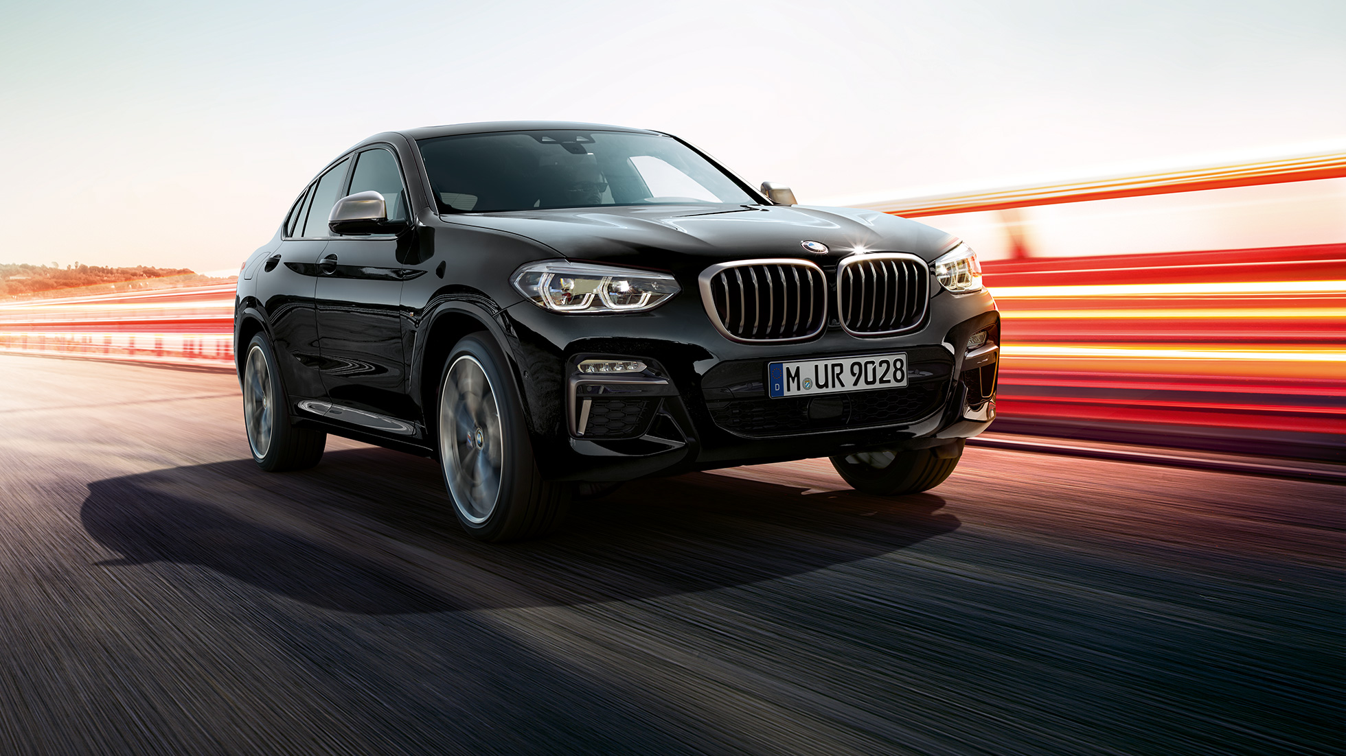 BMW X4 M40i un BMW X4 M40d, trīs ceturtdaļu skats no priekšpuses. BMW X4 M40i un BMW X4 M40d metāliskā Black Sapphire krāsā, virsbūve, trīs ceturtdaļu skats no priekšpuses, kreisais sāns ar gaismas joslām.