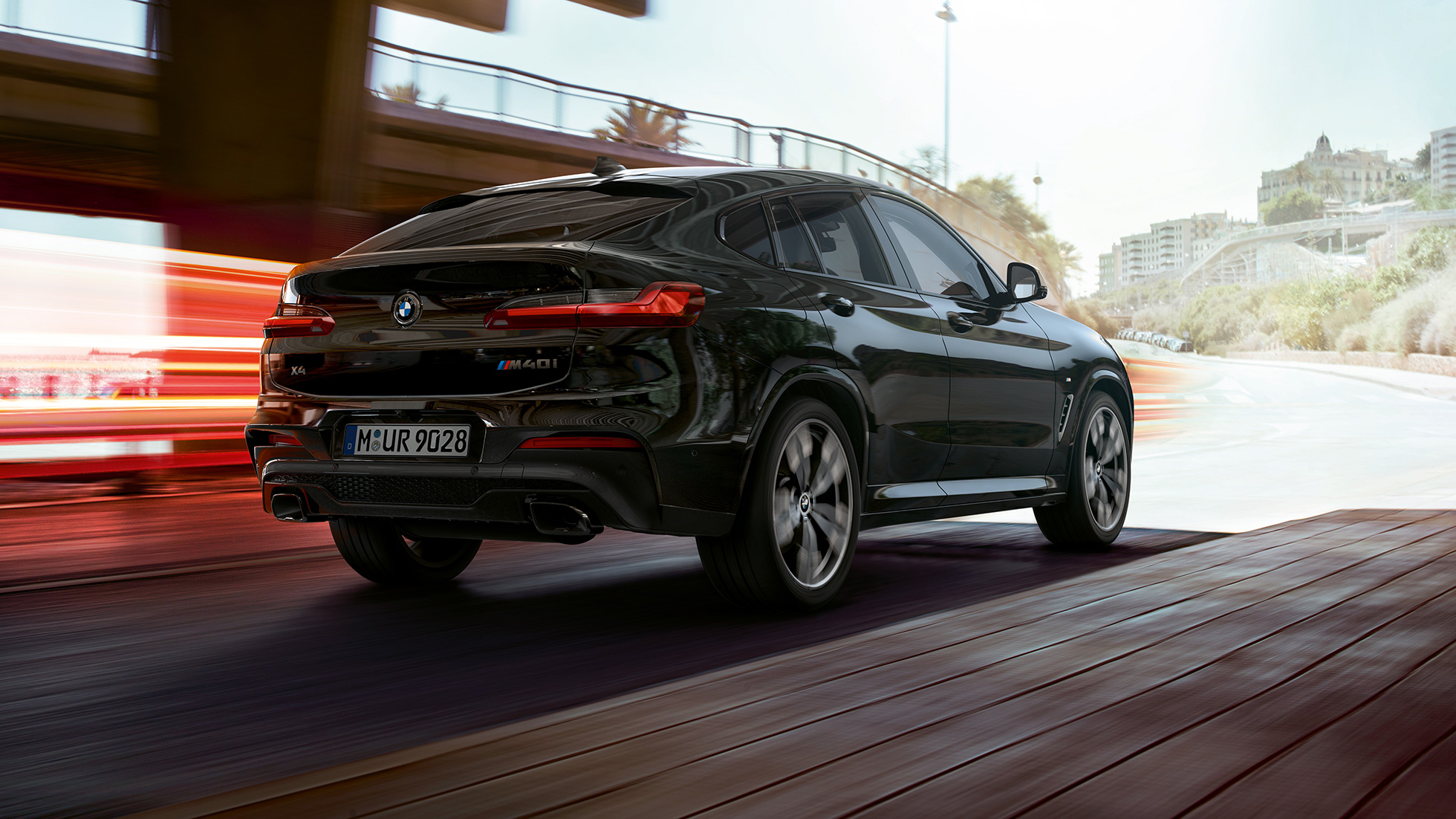 BMW X4 M40i, trīs ceturtdaļu skats no aizmugures. BMW X4 M40i metāliskā Black Sapphire krāsā, virsbūve, trīs ceturtdaļu skats no aizmugures, labais sāns ar gaismas joslām.