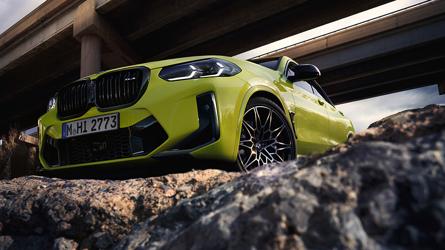 BMW X4 M Competition, F98, LCI, atjaunināts, 2021, Sao Paulo Yellow krāsa, trīs ceturtdaļu priekšpuses skats ar skatu no apakšas, zem tiltiem