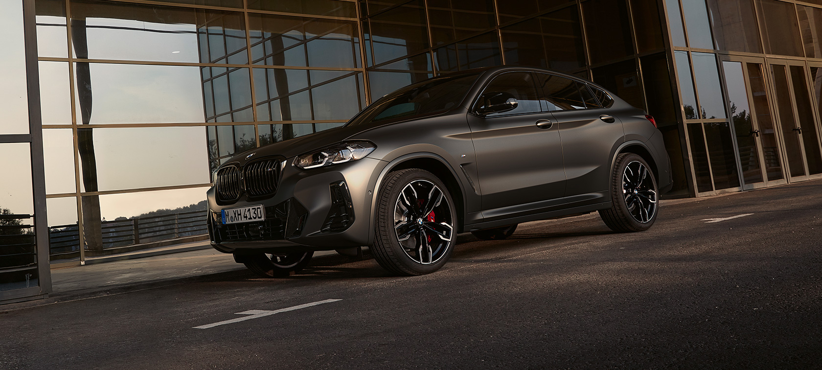 BMW X4 M40i, G02, LCI, 2021, atjaunināts, trīs ceturtdaļu priekšpuses skats, uz stikla fasādes fona