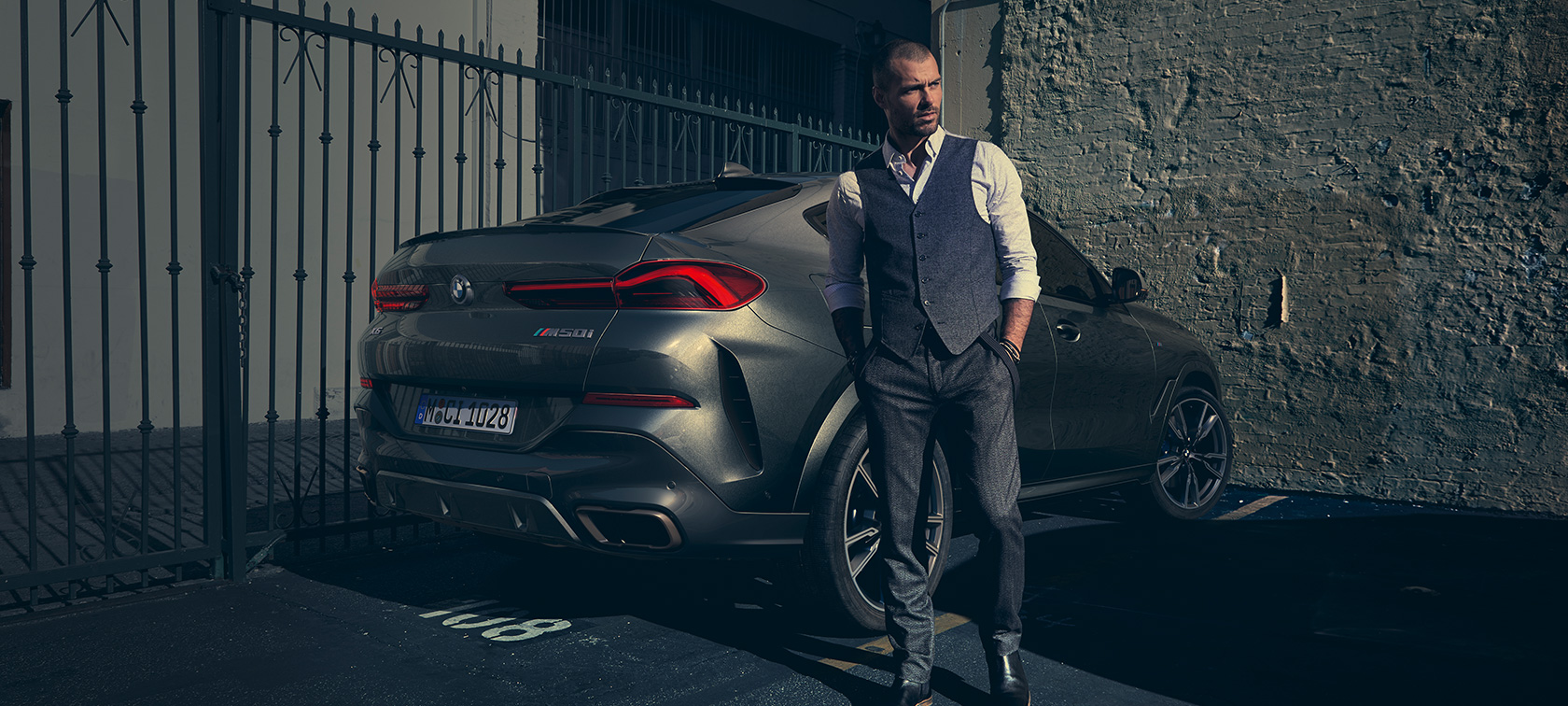 BMW X6 M50i trīs ceturtdaļu aizmugures skatā, G06 Vīrietis, kurš stāv blakus BMW X6 M50i G06, 2018, SUV trīs ceturtdaļu aizmugures skatā