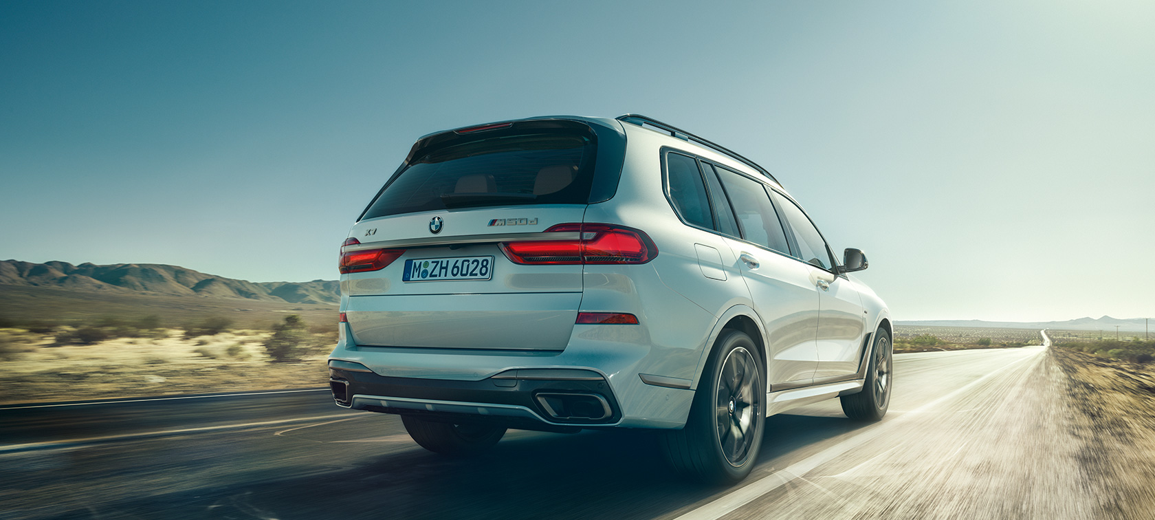 BMW X7 M50d, aizmugures skats BMW X7 M50d Mineral White krāsā, braucot pa tukšu automaģistrāli, aizmugures skats, G07, 2019