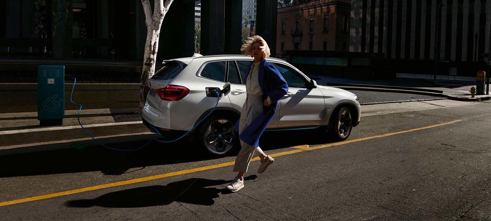 BMW iX3 G08, 2020, publiskā uzlādes stacijā, sānskats BMW iX3 G08, 2020, metāliska Mineral White krāsa, publiskā uzlādes stacijā, sānskats