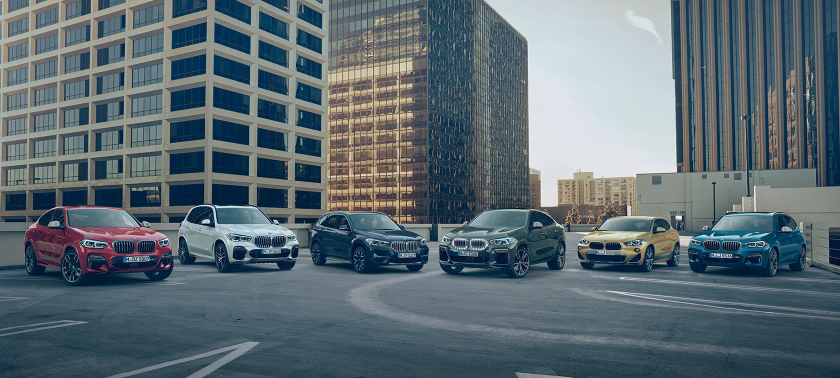BMW X automobiļi atklātā stāvvietā uz ēku fona BMW X sērija, BMW X automobiļi atklātā stāvvietā uz ēku fona