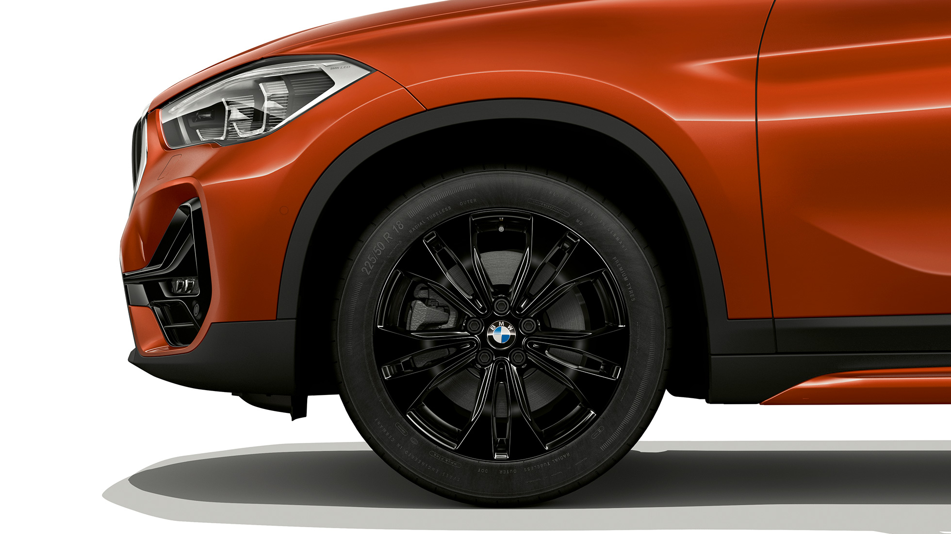 BMW X1, Sport Line modelis, vieglmetāla disks. BMW X1, Sport Line modelis, skats no sāniem ar vieglmetāla diska tuvplānu.